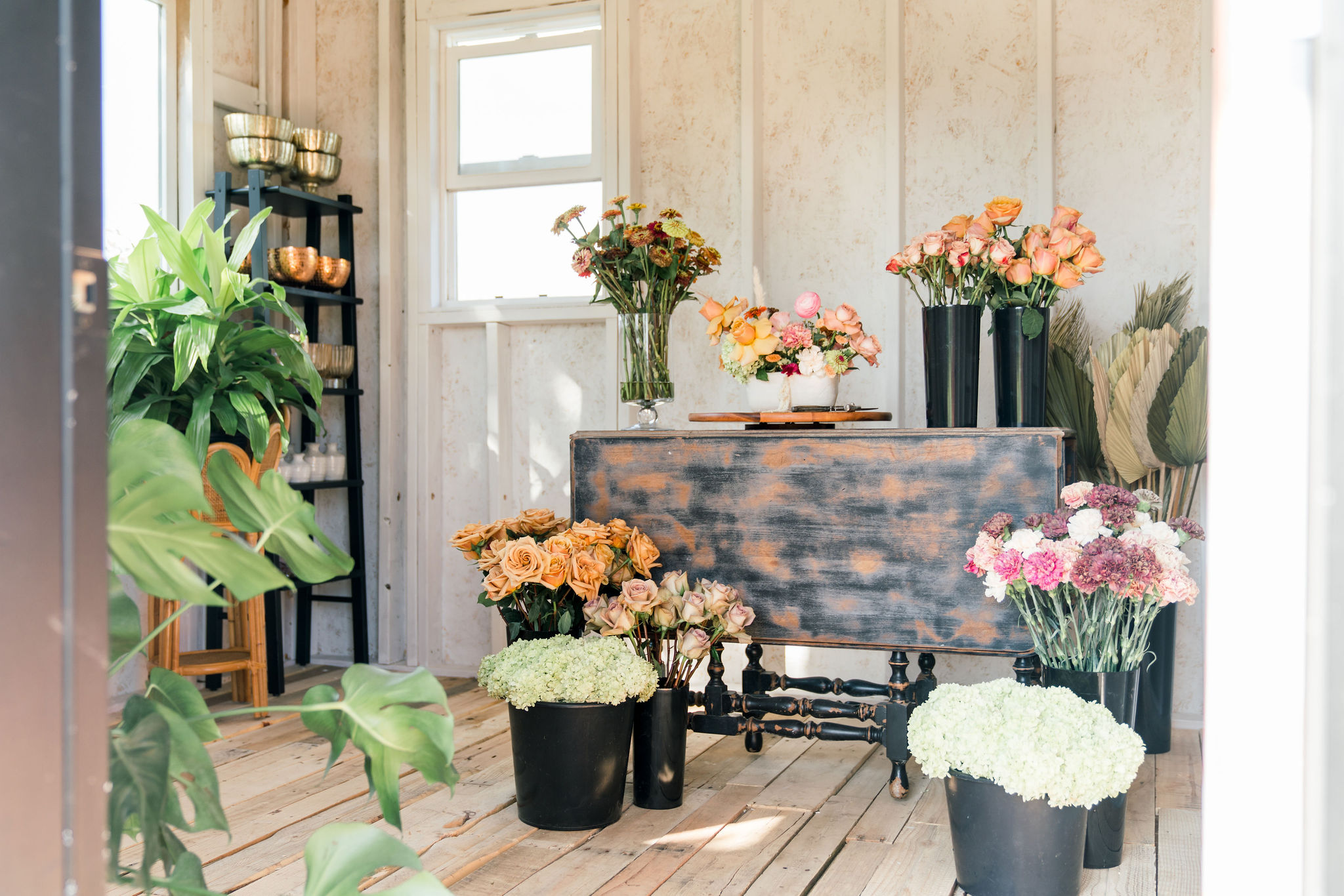 Several floral arrangements sitting on the floor and on top of a